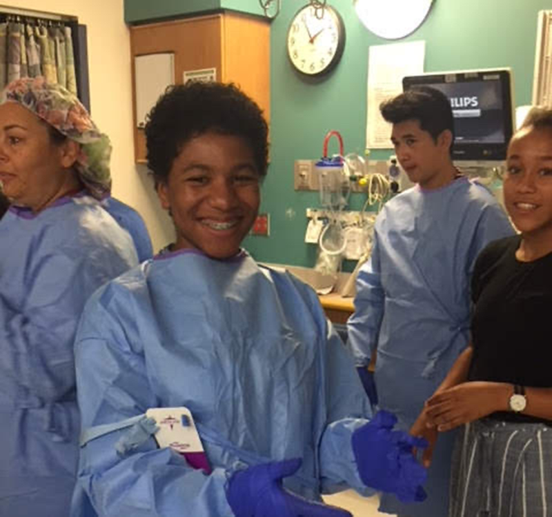 Student Matijanay Tiggle in hospital scrubs standing with three other individuals in scrubs
